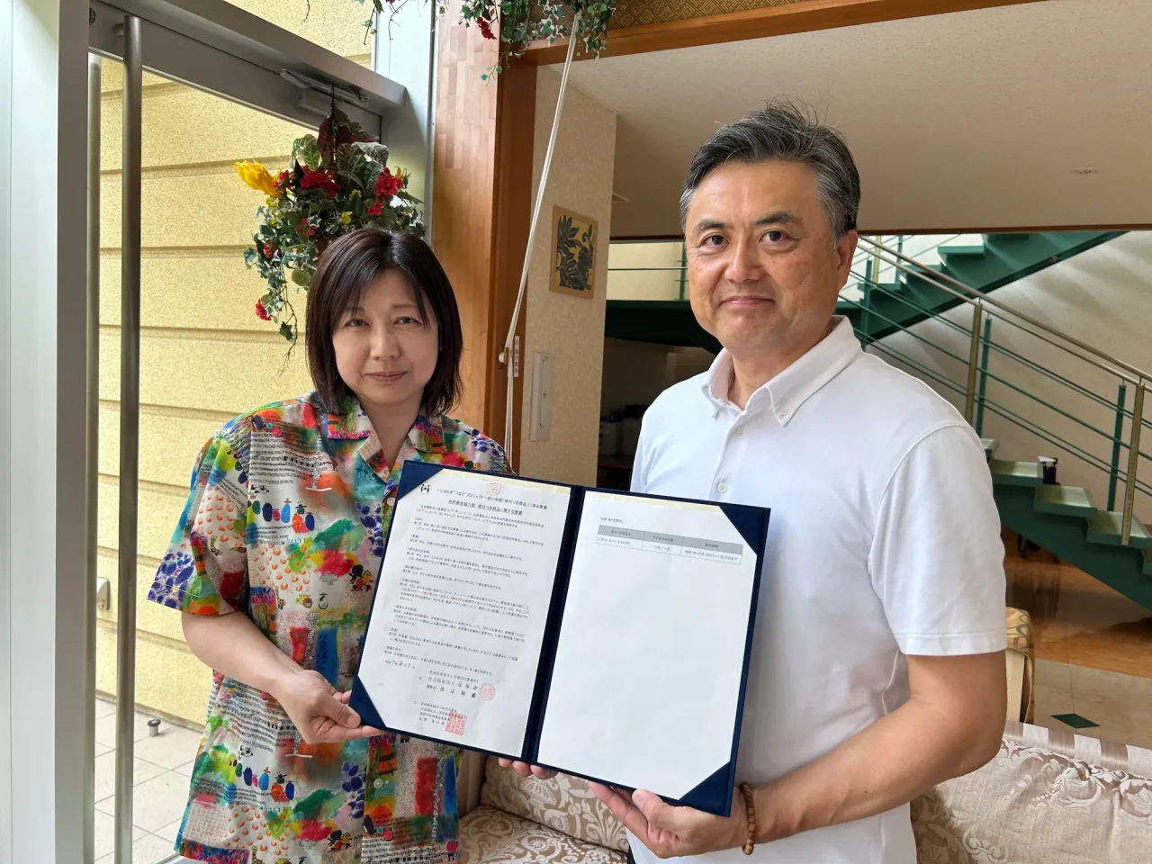社会福祉法人征峯会の事務長と赤い羽根共同募金の担当者が協定書を持って並んでいる様子