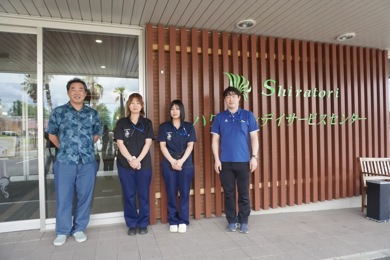 しらとりハワイアンデイサービスセンターの正面玄関前で並ぶ社会福祉法人盡誠会と征峯会のスタッフ一同