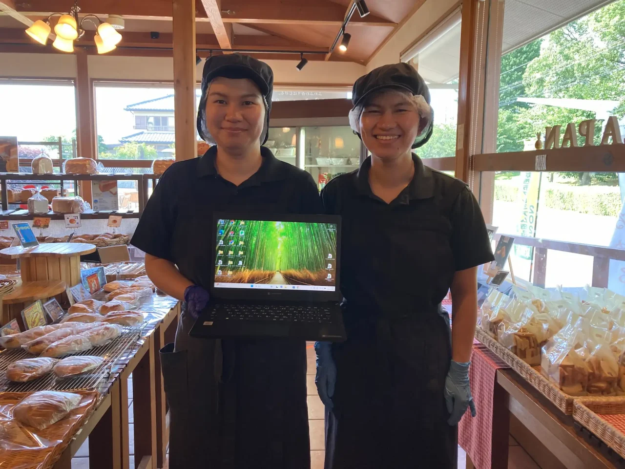 購入したノートパソコンを笑顔で抱えるCAFEラパンのスタッフ2名