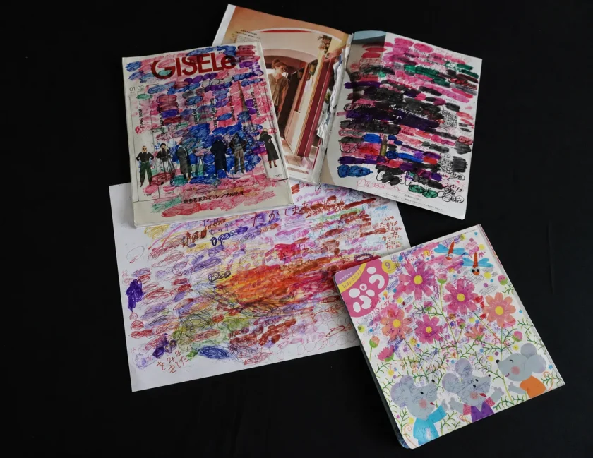 既存の雑誌「GISELe」や絵本の上に、マーカーやクレヨンで自由に線が描かれ切り抜きが貼られた作品